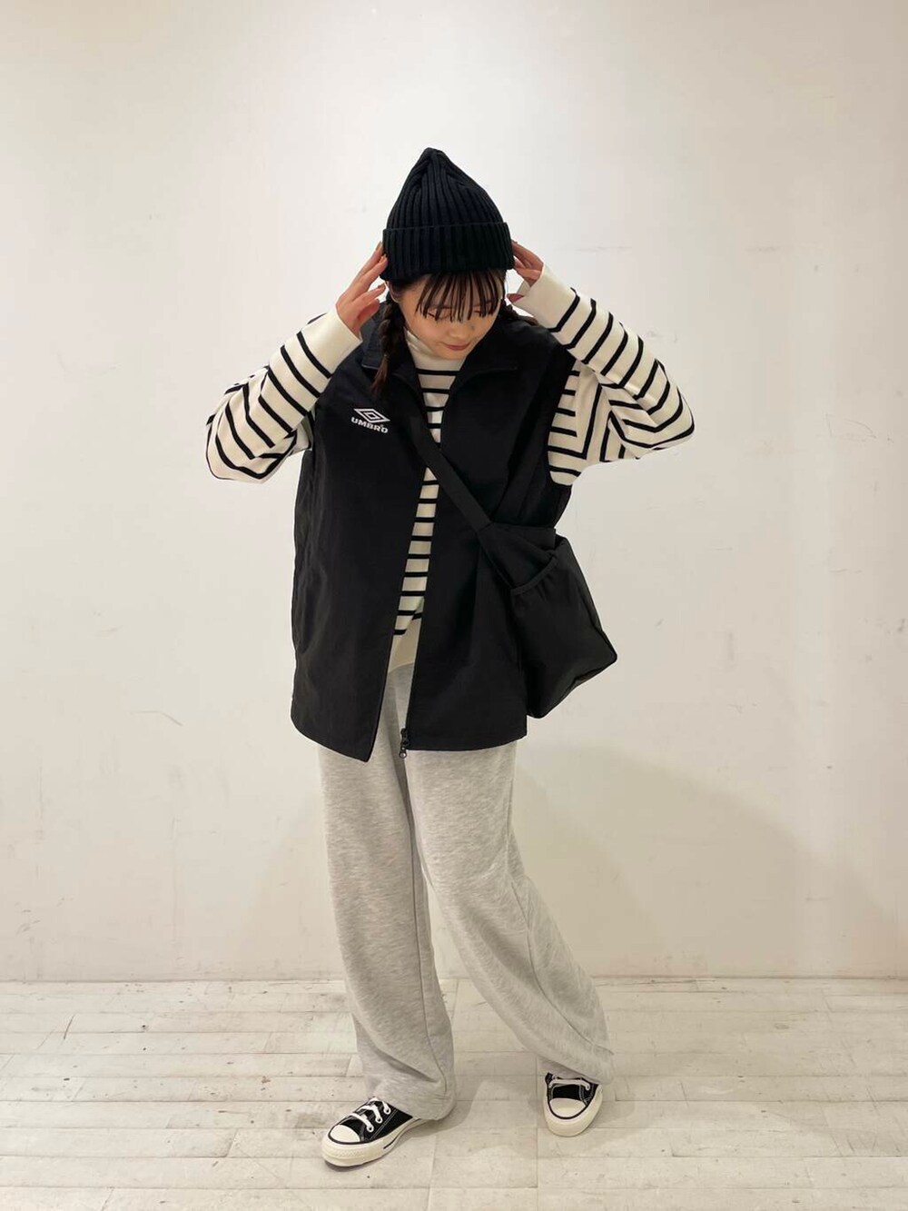 ブラック系のスニーカー、ブラック系のショルダーバッグ、ブラック系のベストを着用したレディースの秋コーディネートの2枚目の写真