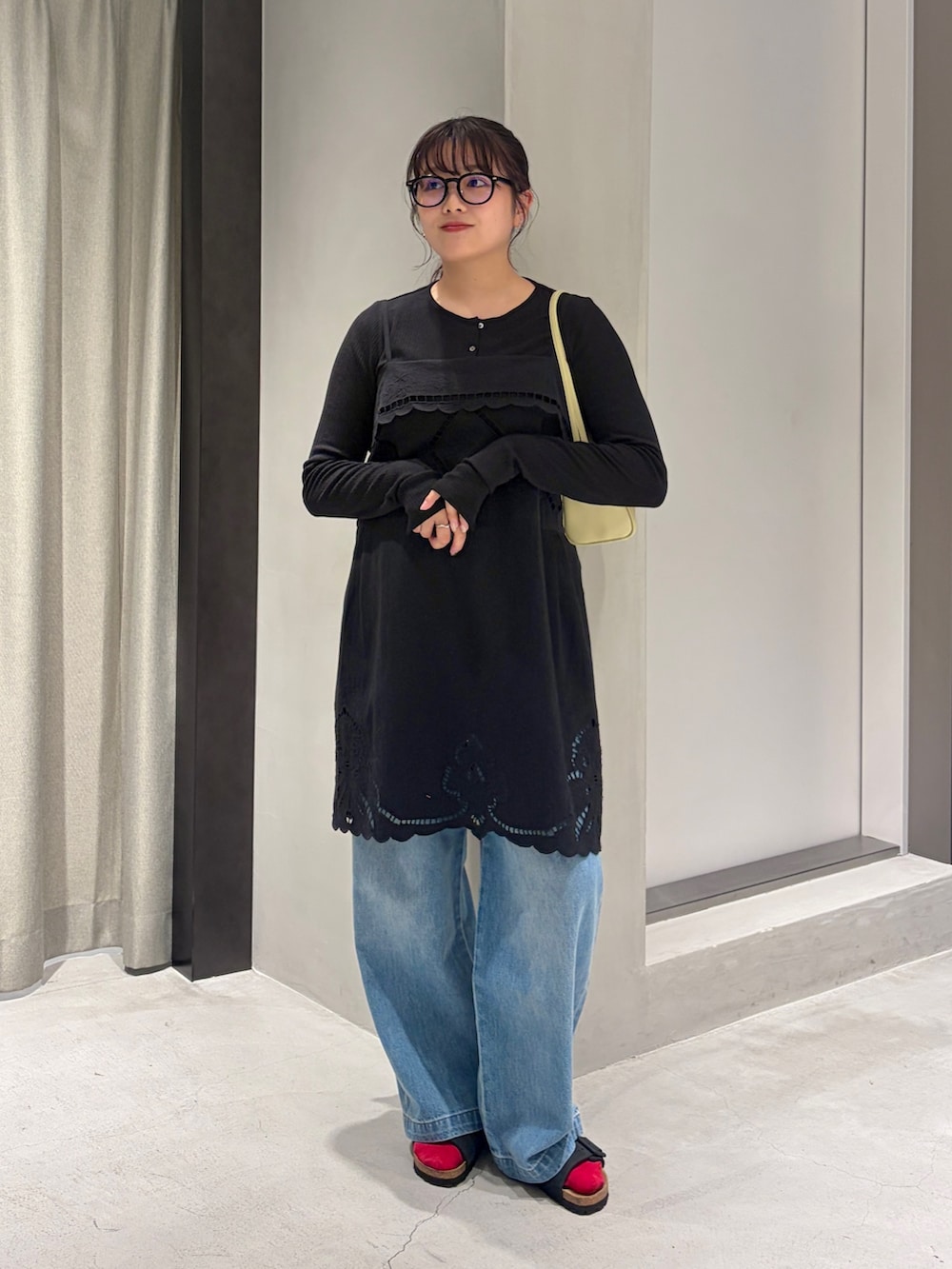 ブルー系のデニムパンツ、ブラック系のカーディガン/ボレロ、イエロー系のハンドバッグを着用したレディースの夏コーディネートの2枚目の写真