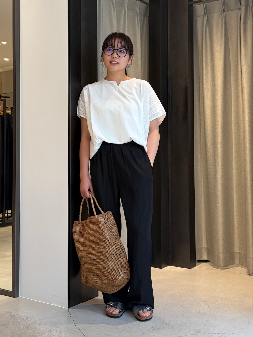 ブラック系のその他パンツ、ホワイト系のその他トップス、ブラウン系のかごバッグを着用したレディースの夏コーディネートの2枚目の写真