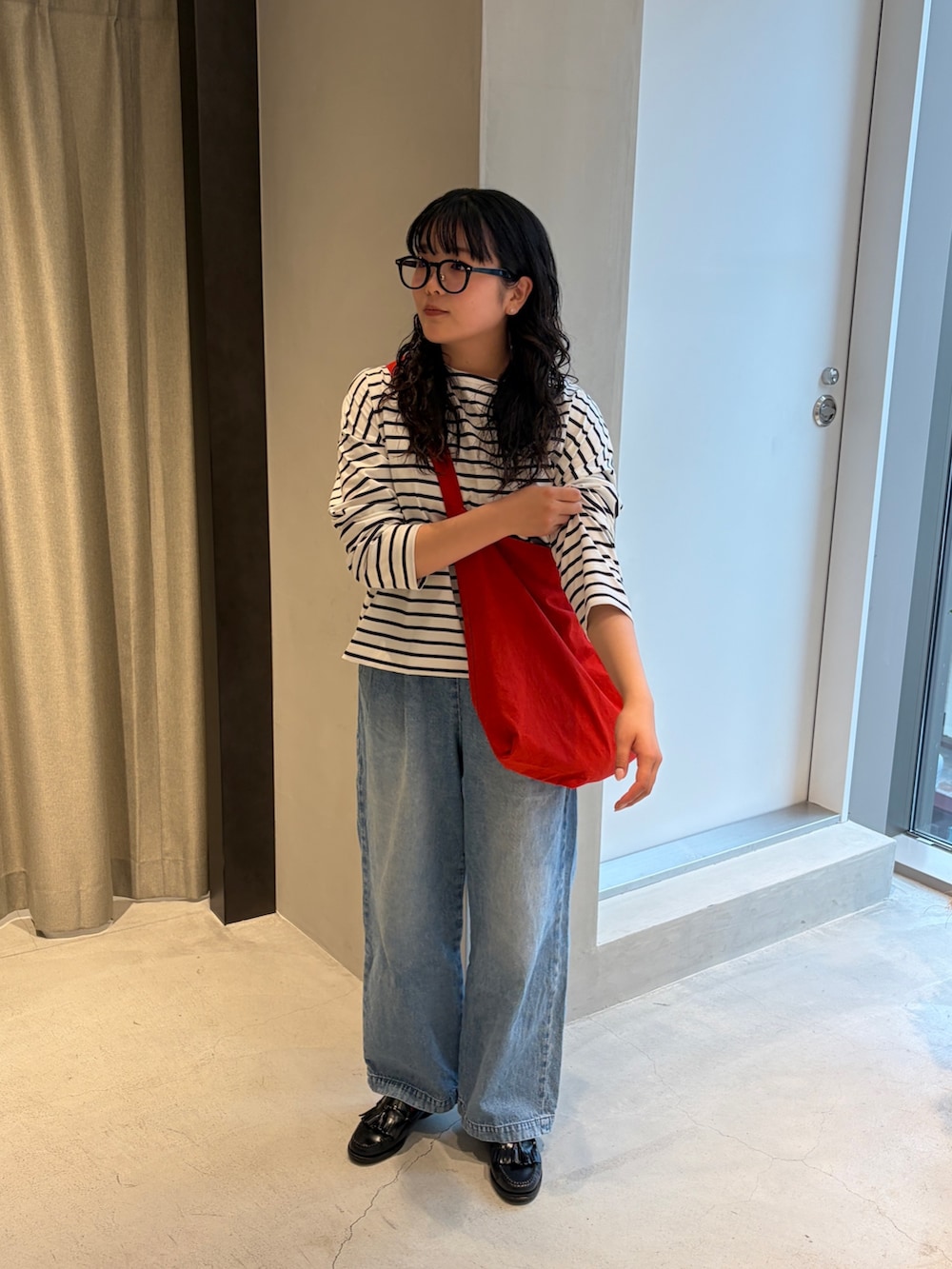 レッド系のショルダーバッグ、ブルー系のデニムパンツ、ブラック系のTシャツ/カットソーを着用したレディースの春コーディネートの2枚目の写真