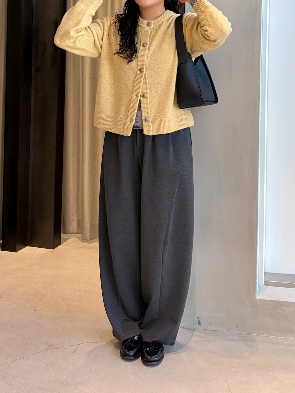 グレー系のその他パンツ、イエロー系のカーディガン/ボレロ、ブラック系のハンドバッグを着用したレディースの秋コーディネートの3枚目の写真