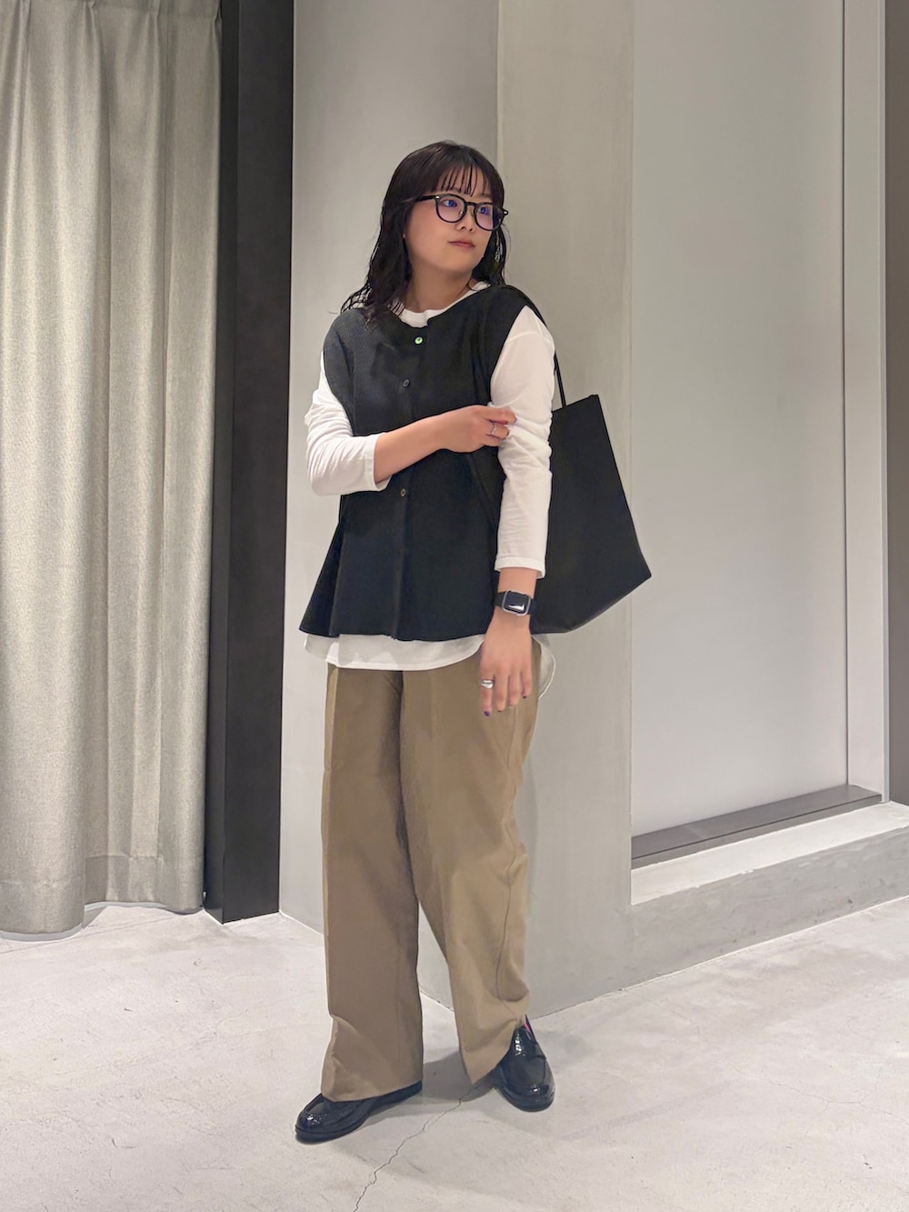グレー系のベスト、ホワイト系のTシャツ/カットソー、ブラック系のトートバッグを着用したレディースの秋コーディネートの2枚目の写真