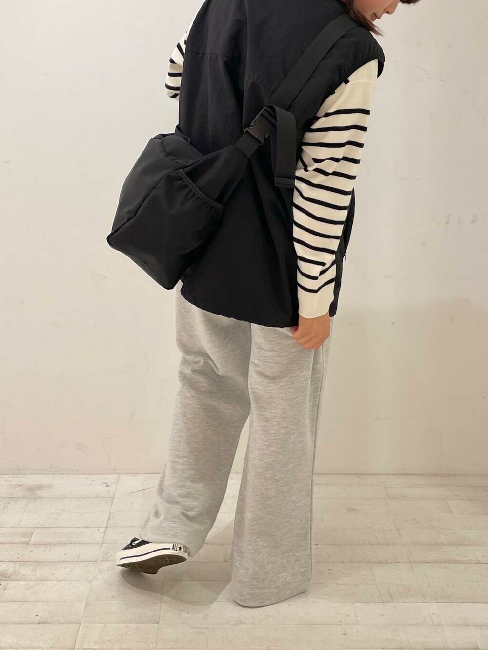 ブラック系のスニーカー、ブラック系のショルダーバッグ、ブラック系のベストを着用したレディースの秋コーディネートの6枚目の写真