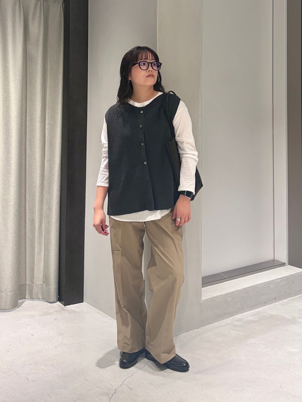 グレー系のベスト、ホワイト系のTシャツ/カットソー、ブラック系のトートバッグを着用したレディースの秋コーディネートの4枚目の写真
