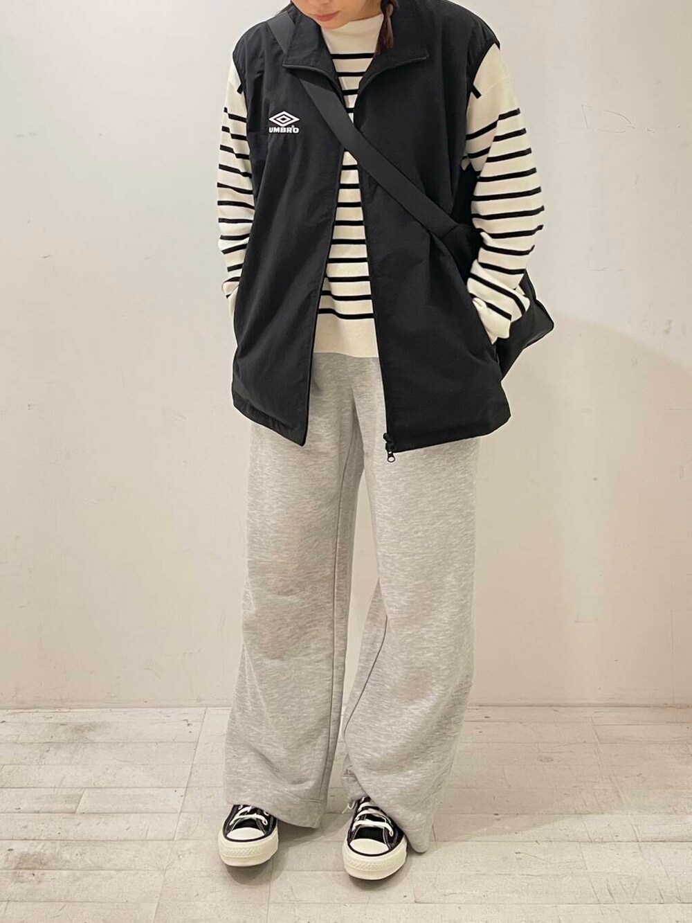 ブラック系のスニーカー、ブラック系のショルダーバッグ、ブラック系のベストを着用したレディースの秋コーディネートの5枚目の写真