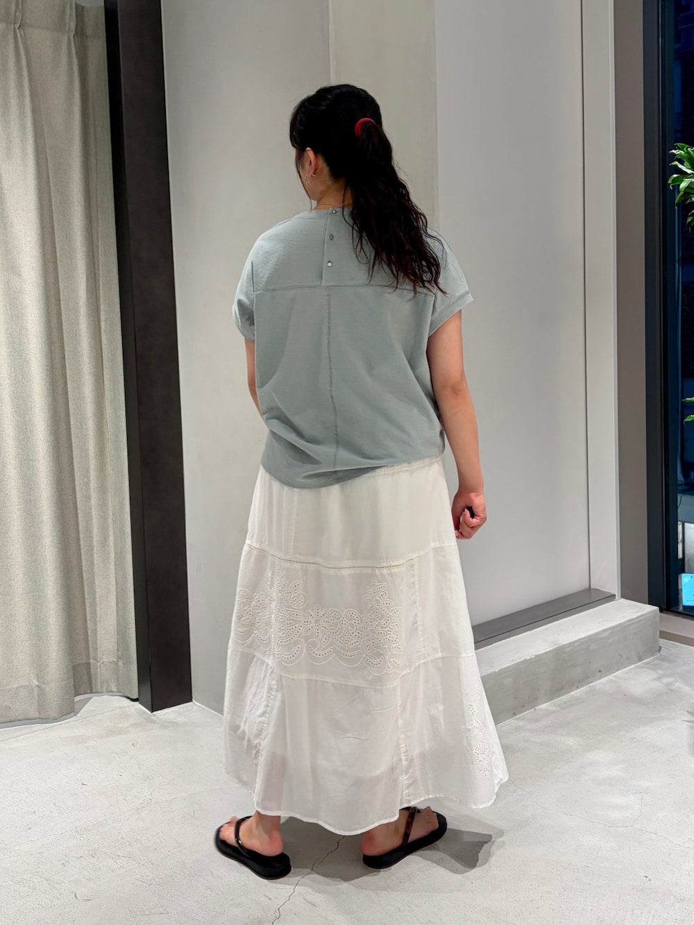 ホワイト系のスカート、ブラック系のサンダル、グリーン系のTシャツ/カットソーを着用したレディースの夏コーディネートの2枚目の写真