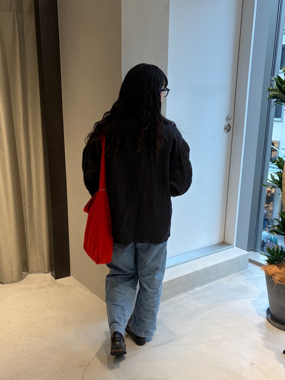レッド系のショルダーバッグ、ブルー系のデニムパンツ、ブラック系のTシャツ/カットソーを着用したレディースの春コーディネートの6枚目の写真