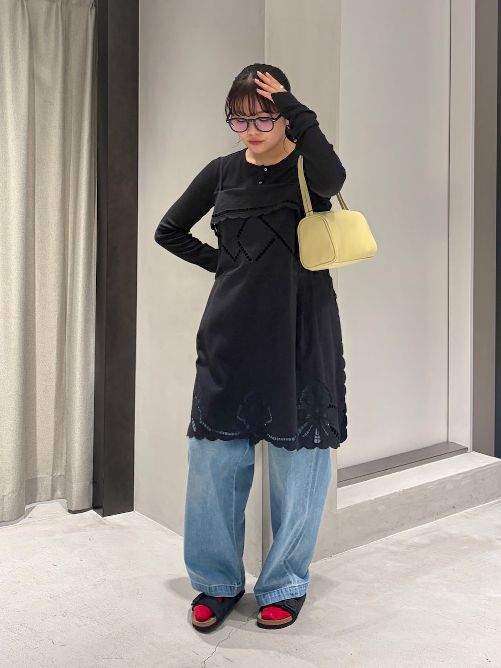 ブルー系のデニムパンツ、ブラック系のカーディガン/ボレロ、イエロー系のハンドバッグを着用したレディースの夏コーディネートの4枚目の写真