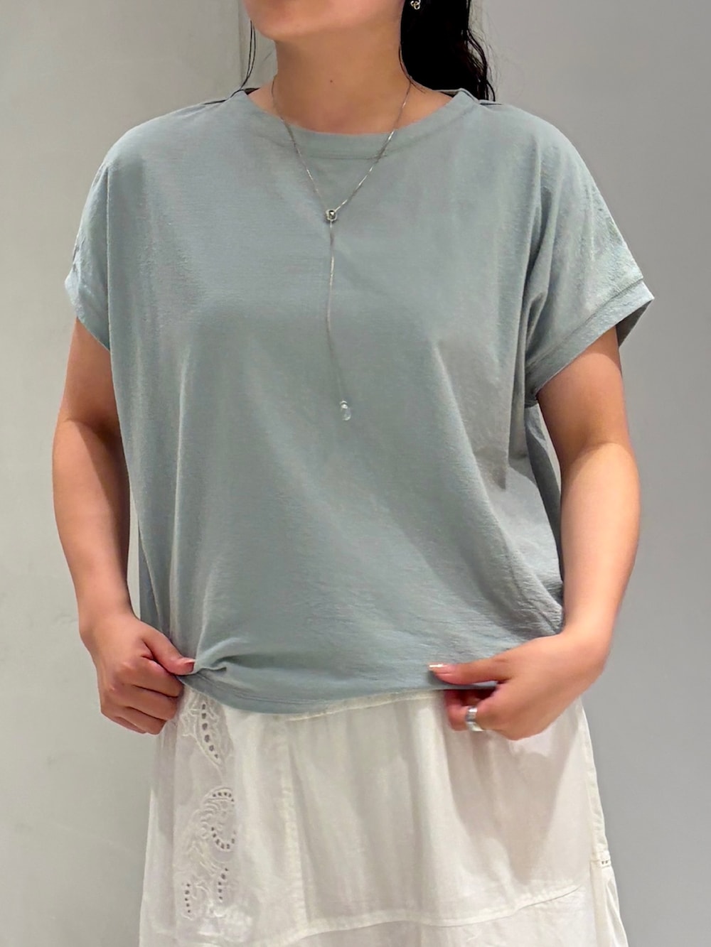 ホワイト系のスカート、ブラック系のサンダル、グリーン系のTシャツ/カットソーを着用したレディースの夏コーディネートの6枚目の写真
