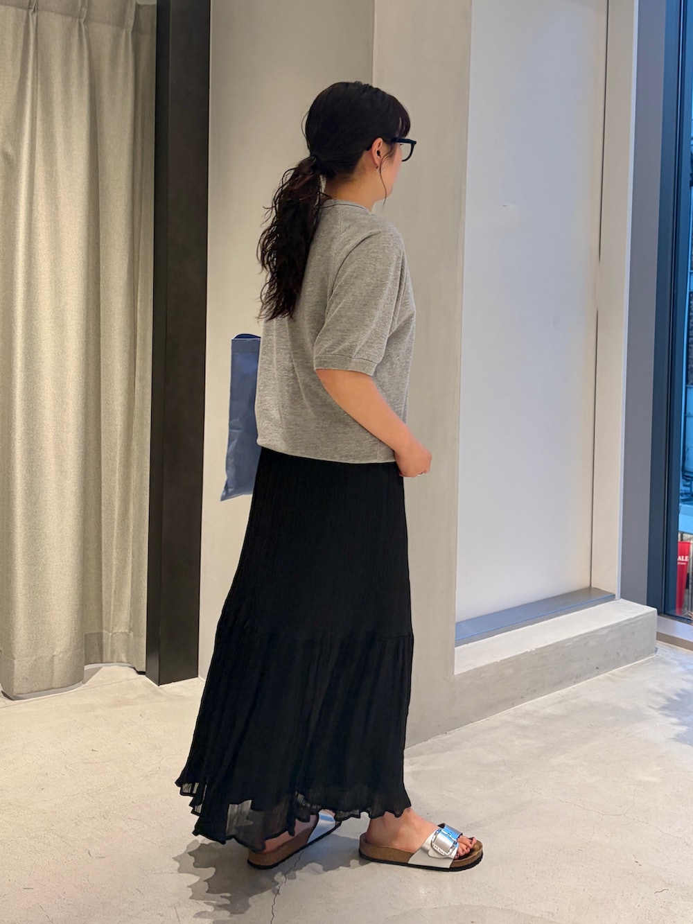 グレー系のシャツ/ブラウス、ブルー系のトートバッグ、ブラック系のスカートを着用したレディースの夏コーディネートの2枚目の写真
