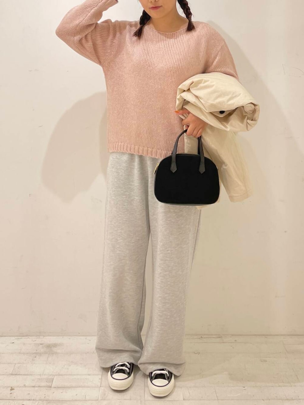 ブラック系のスニーカー、ブラック系のショルダーバッグ、ピンク系のニット/セーターを着用したレディースの秋コーディネートの2枚目の写真