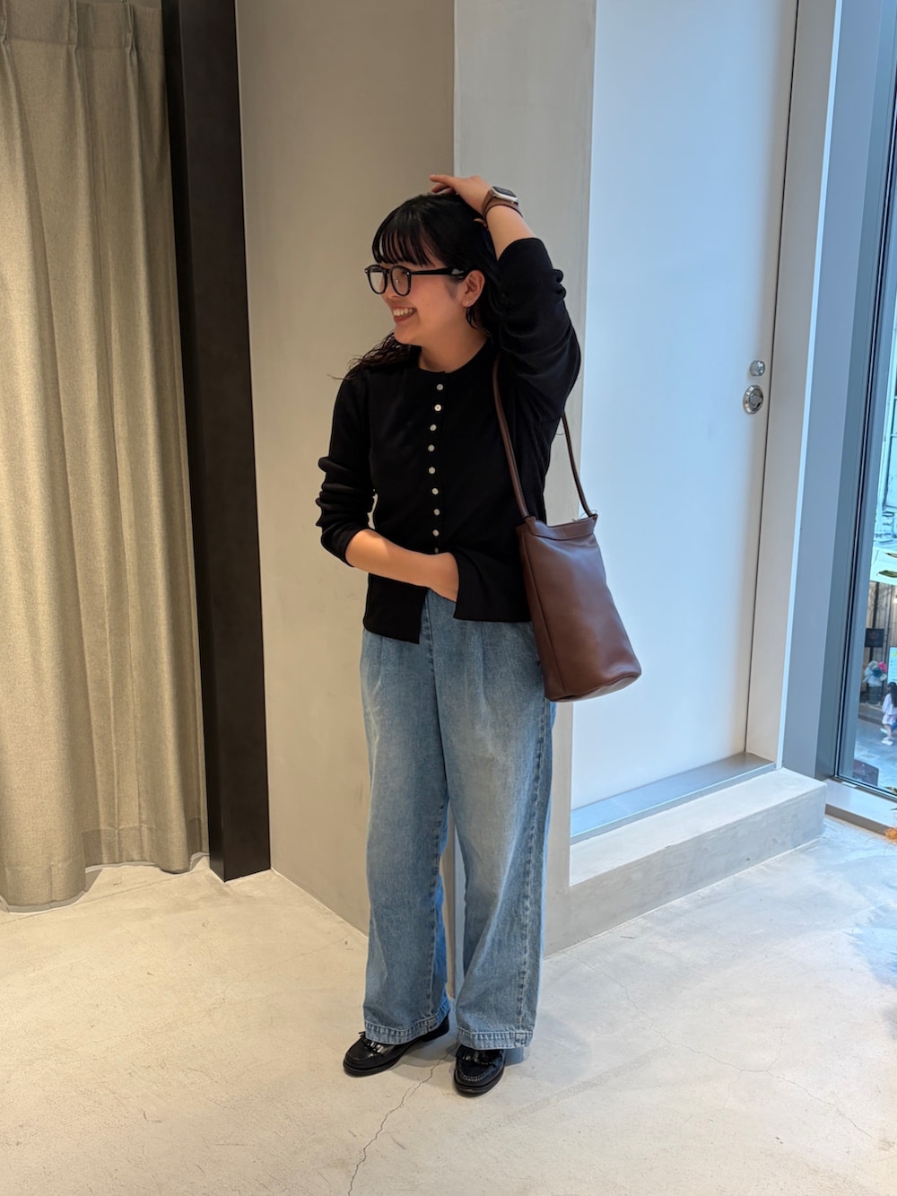 ブラック系のカーディガン/ボレロ、ブルー系のデニムパンツ、ブラウン系のショルダーバッグを着用したレディースの春コーディネートの2枚目の写真