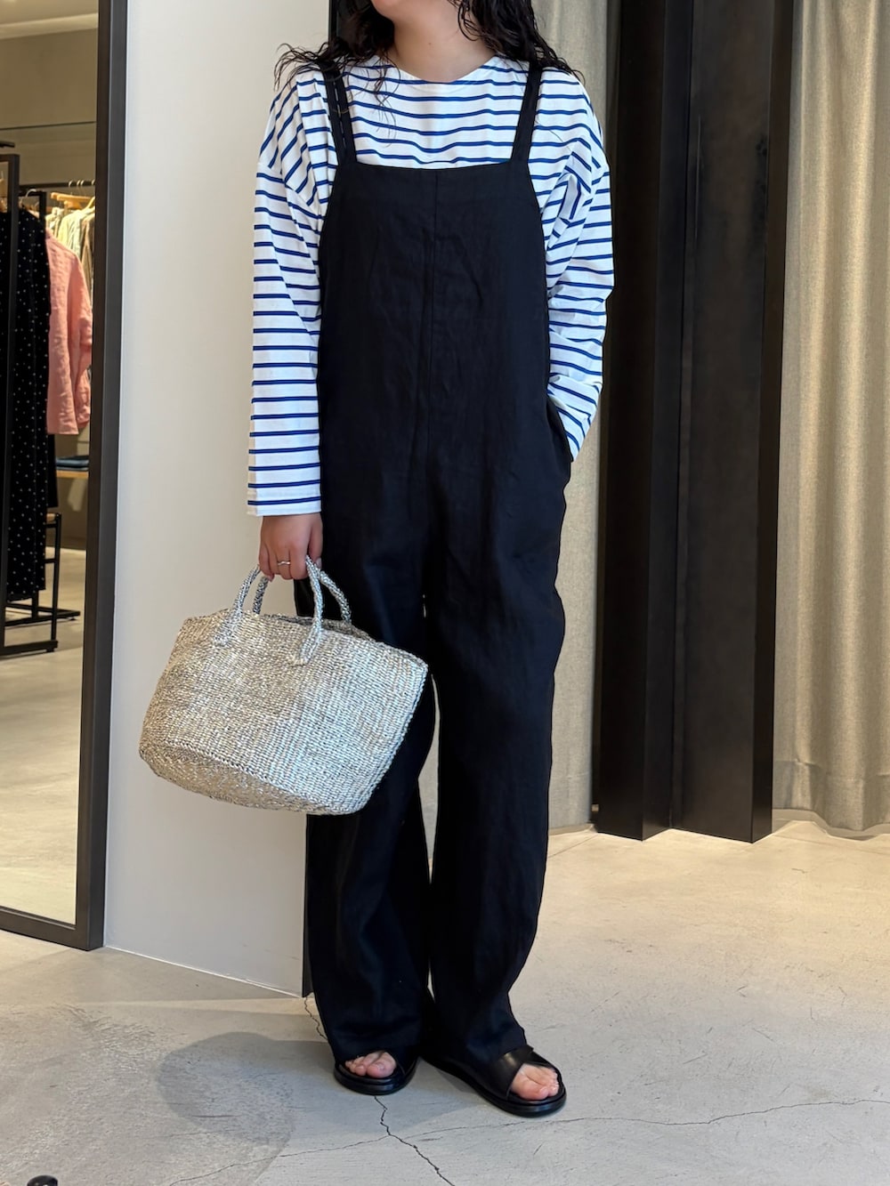 ブラック系のサロペット/オーバーオール、シルバー系のかごバッグ、ブルー系のTシャツ/カットソーを着用したレディースの春コーディネートの2枚目の写真