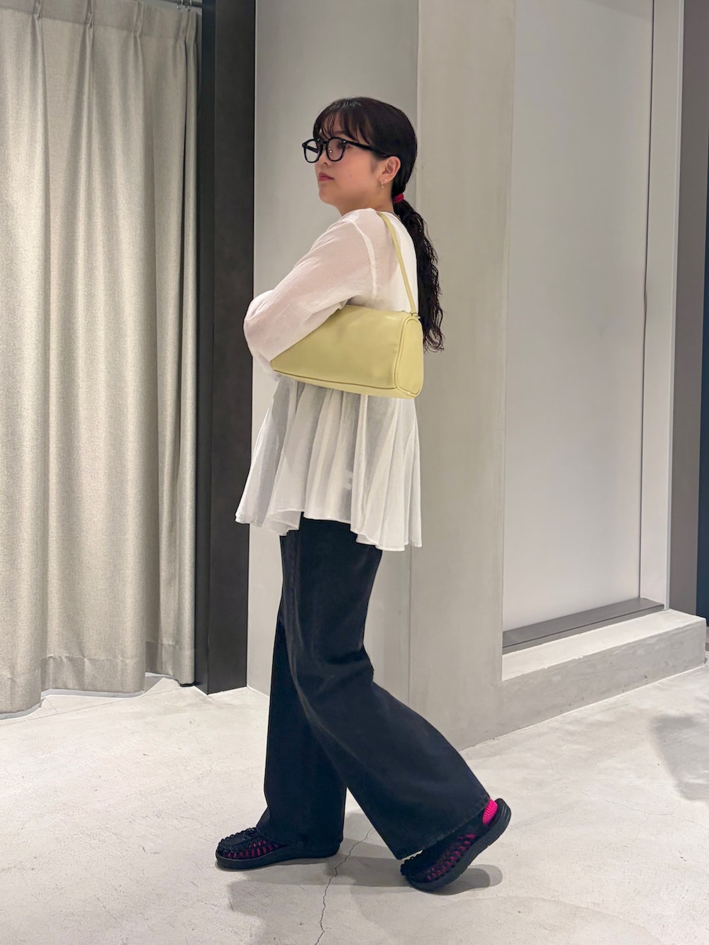 ブラック系のデニムパンツ、イエロー系のハンドバッグ、ホワイト系のシャツ/ブラウスを着用したレディースの夏コーディネートの2枚目の写真