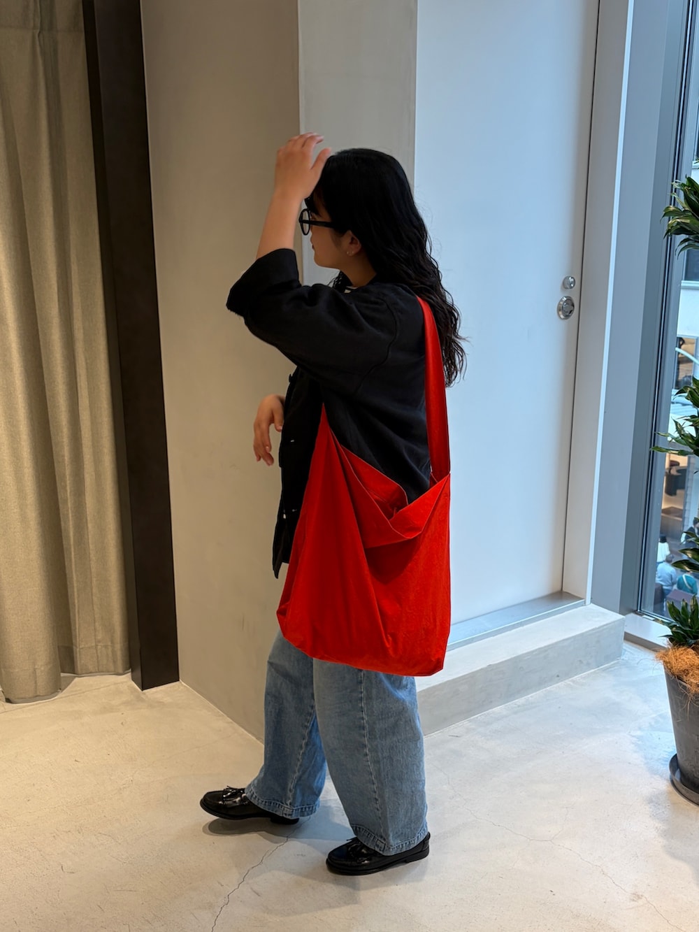 レッド系のショルダーバッグ、ブルー系のデニムパンツ、ブラック系のTシャツ/カットソーを着用したレディースの春コーディネートの5枚目の写真
