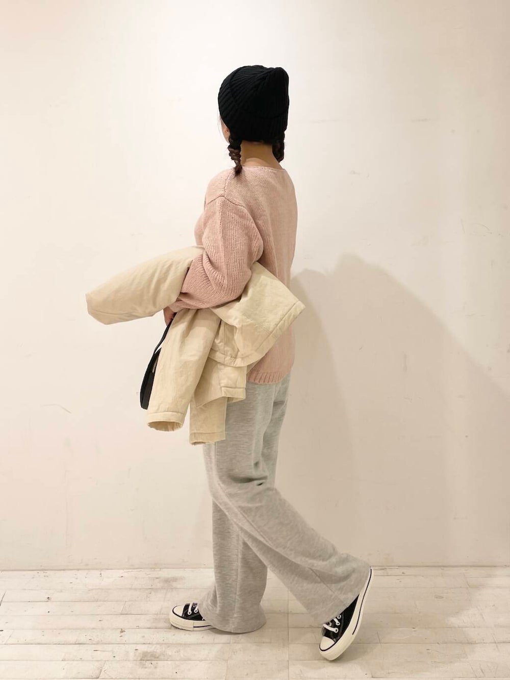 ブラック系のスニーカー、ブラック系のショルダーバッグ、ピンク系のニット/セーターを着用したレディースの秋コーディネートの3枚目の写真