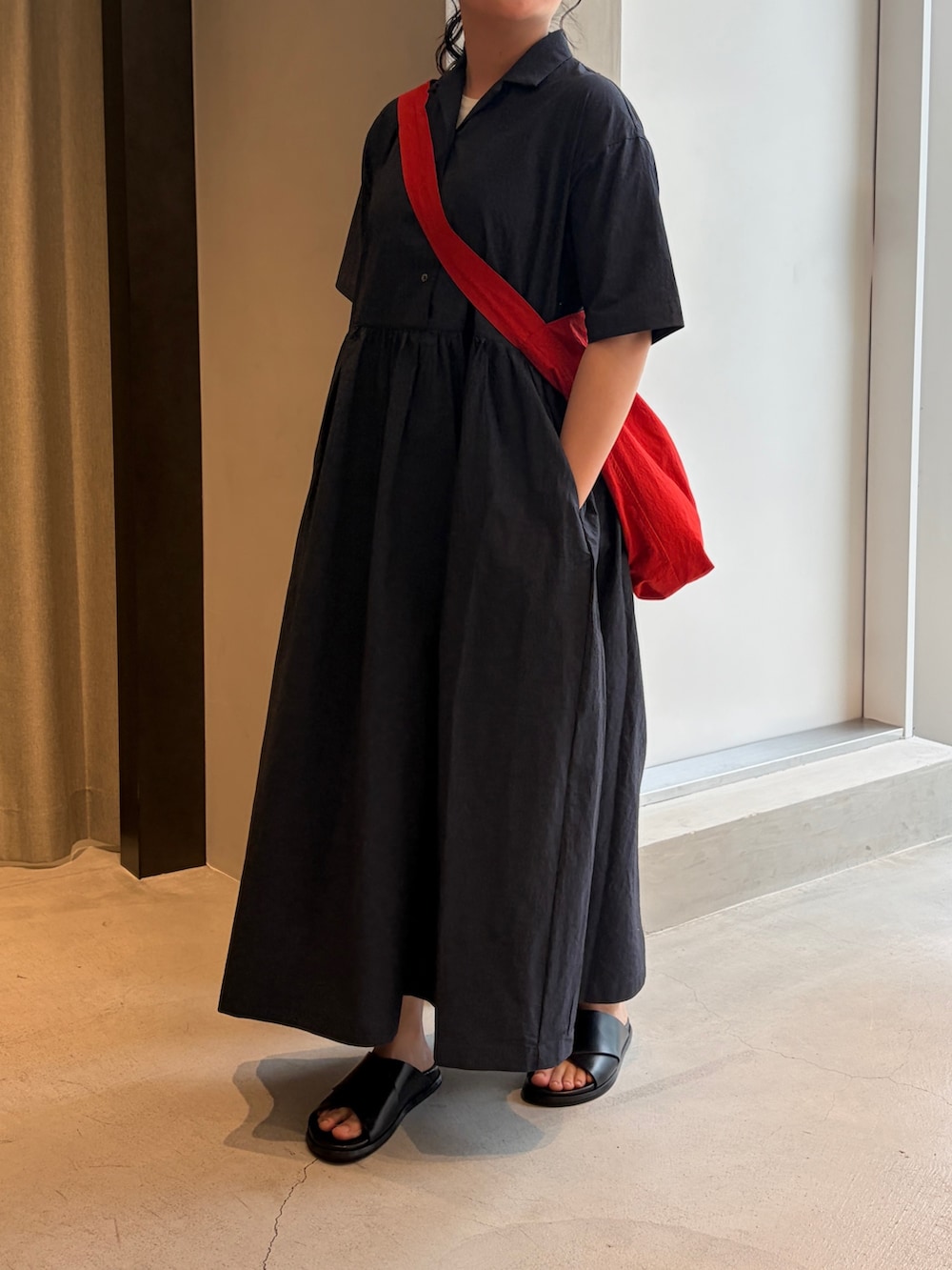 レッド系のショルダーバッグ、ブルー系のワンピース、ブラック系のサンダルを着用したレディースの夏コーディネートの3枚目の写真