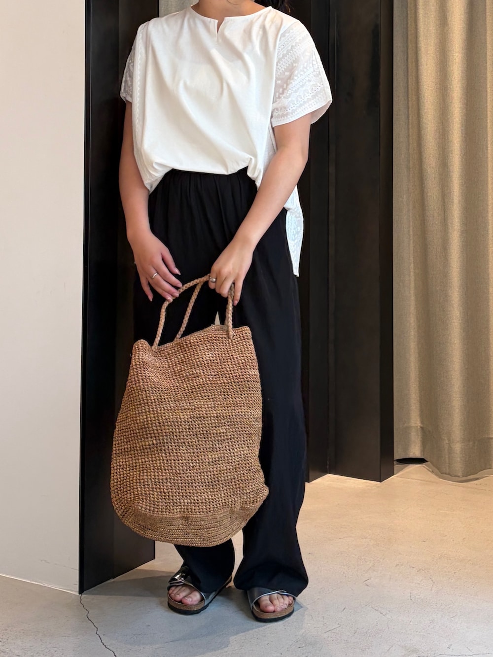 ブラック系のその他パンツ、ホワイト系のその他トップス、ブラウン系のかごバッグを着用したレディースの夏コーディネートの6枚目の写真