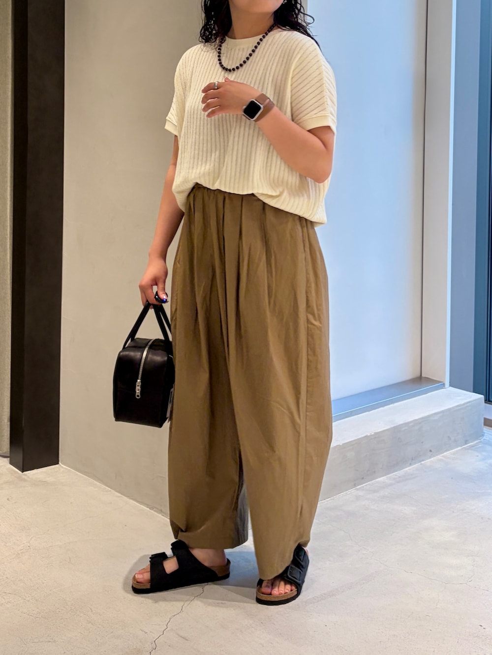 ホワイト系のTシャツ/カットソー、ベージュ系のその他パンツ、ブラック系のハンドバッグを着用したレディースの夏コーディネートの6枚目の写真