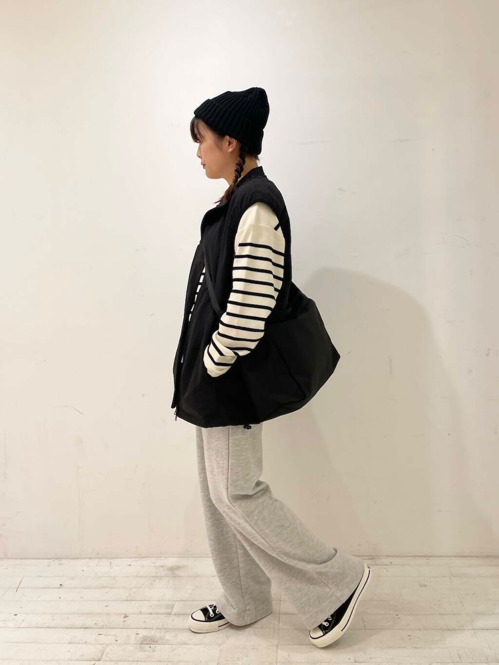 ブラック系のスニーカー、ブラック系のショルダーバッグ、ブラック系のベストを着用したレディースの秋コーディネートの4枚目の写真