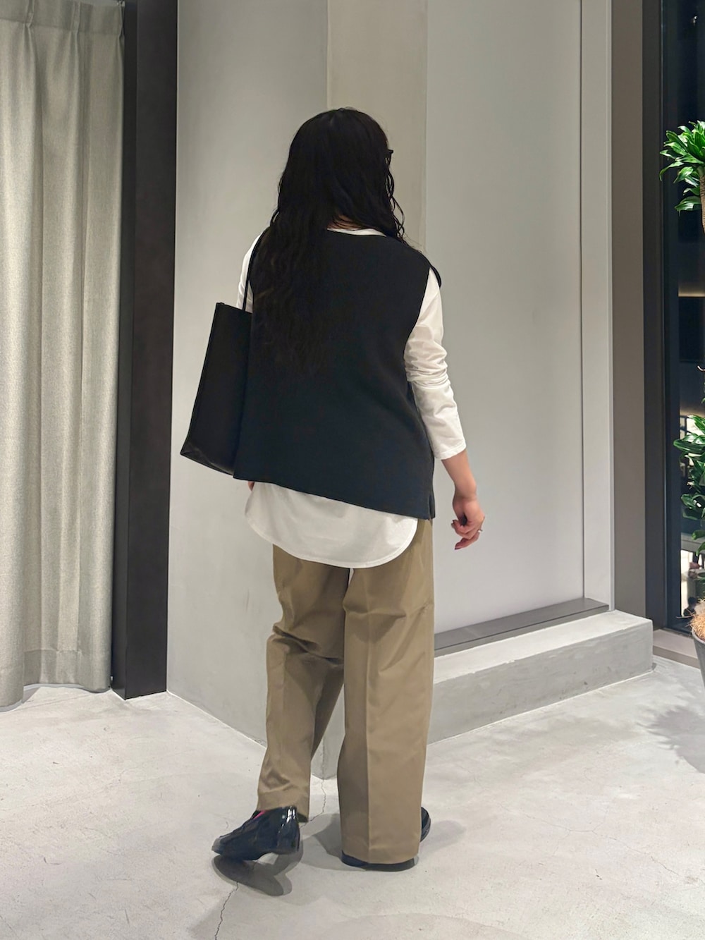 グレー系のベスト、ホワイト系のTシャツ/カットソー、ブラック系のトートバッグを着用したレディースの秋コーディネートの5枚目の写真