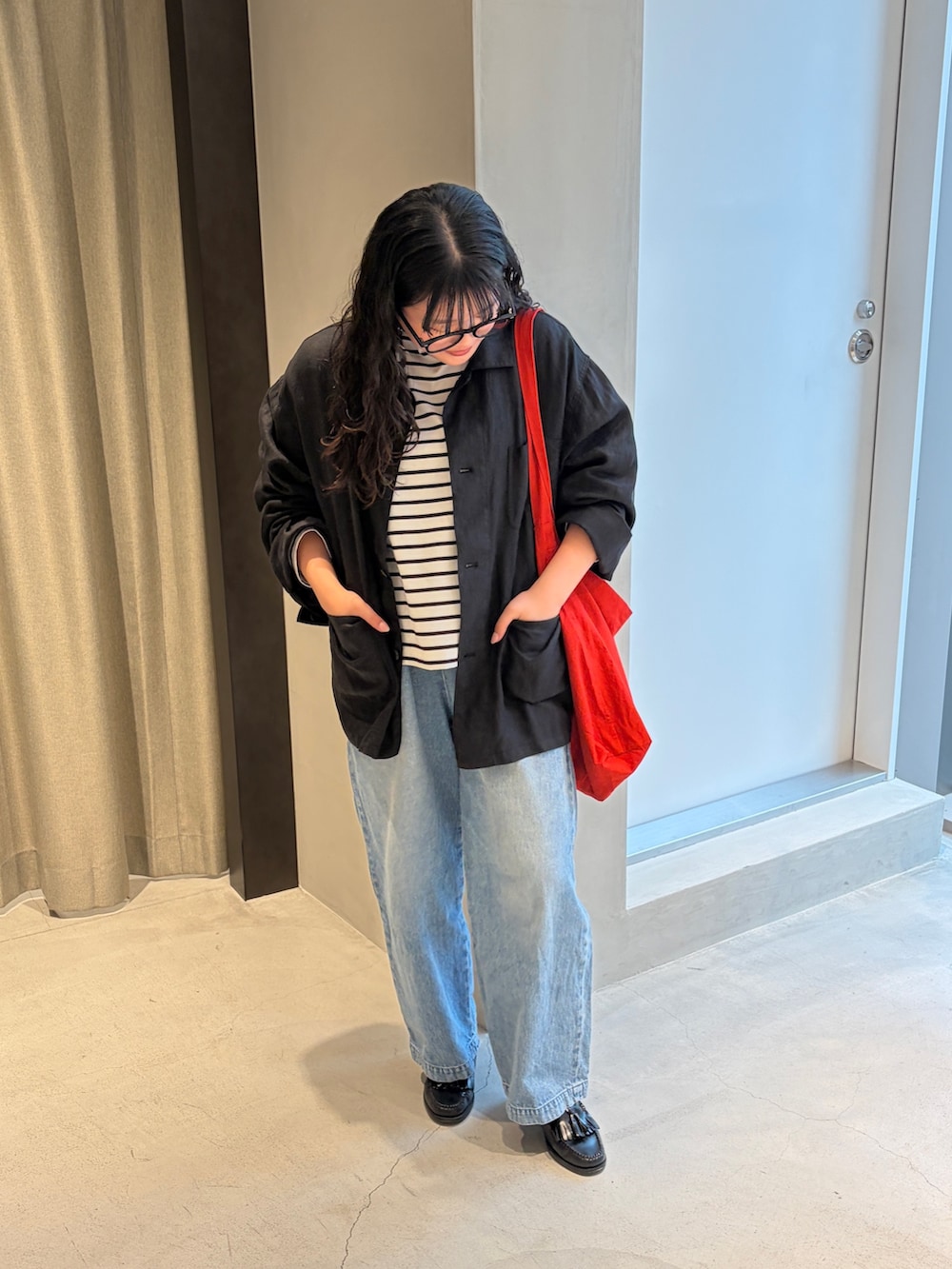 レッド系のショルダーバッグ、ブルー系のデニムパンツ、ブラック系のTシャツ/カットソーを着用したレディースの春コーディネートの4枚目の写真