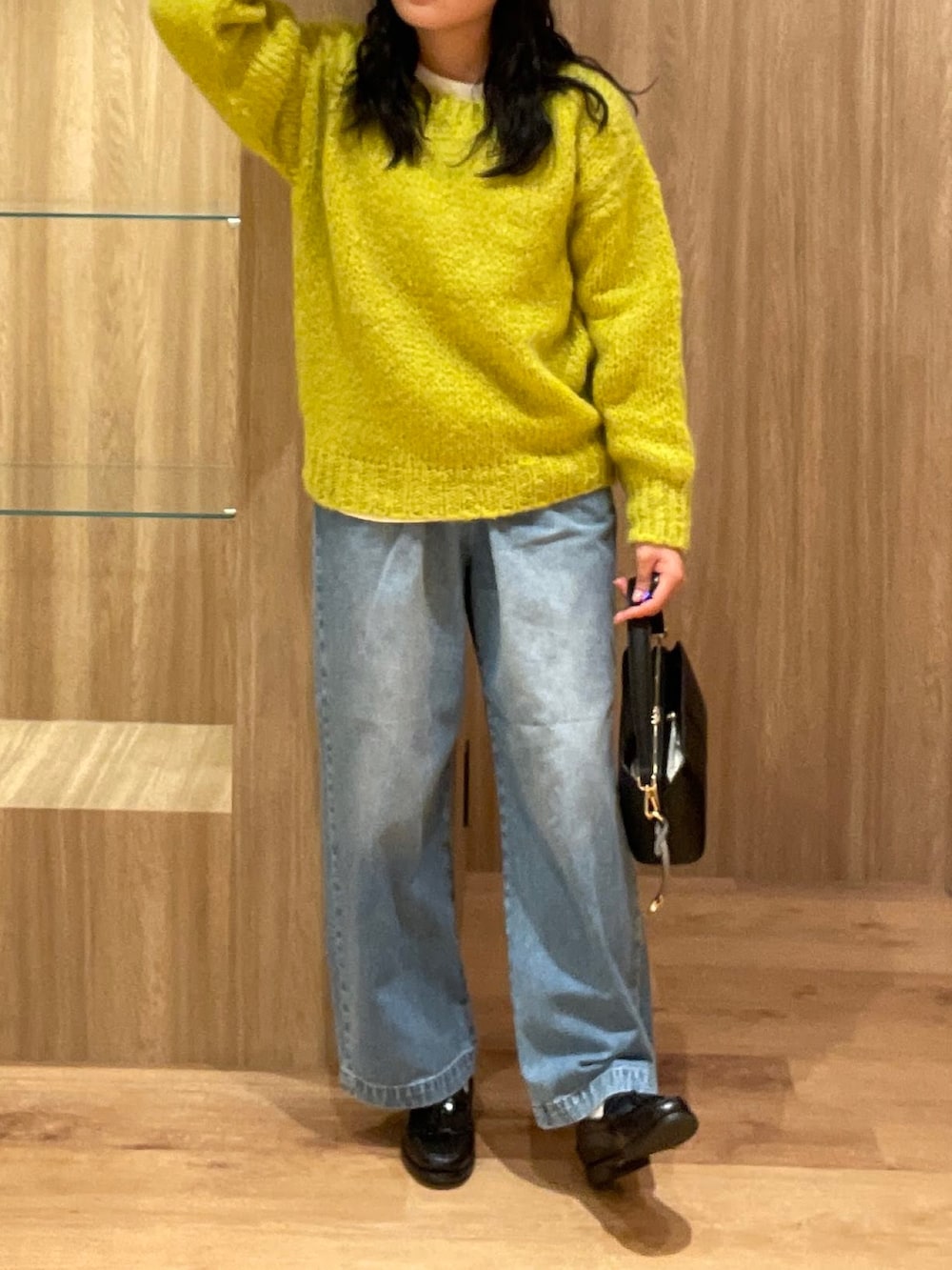 イエロー系のニット/セーター、ブラック系のハンドバッグ、ブルー系のデニムパンツを着用したレディースの冬コーディネートの4枚目の写真