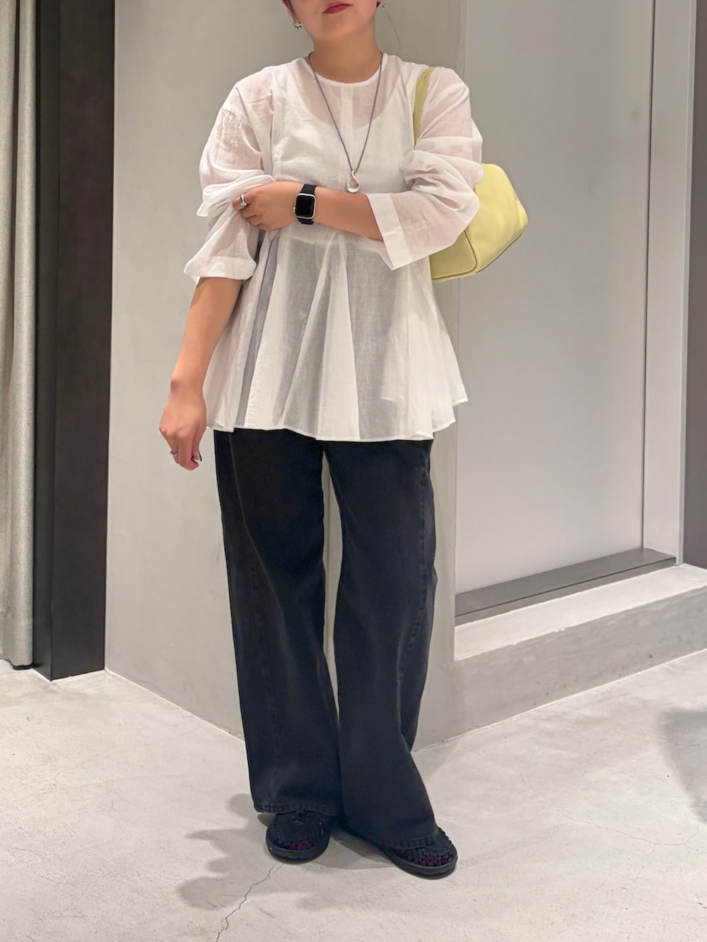 ブラック系のデニムパンツ、イエロー系のハンドバッグ、ホワイト系のシャツ/ブラウスを着用したレディースの夏コーディネートの3枚目の写真