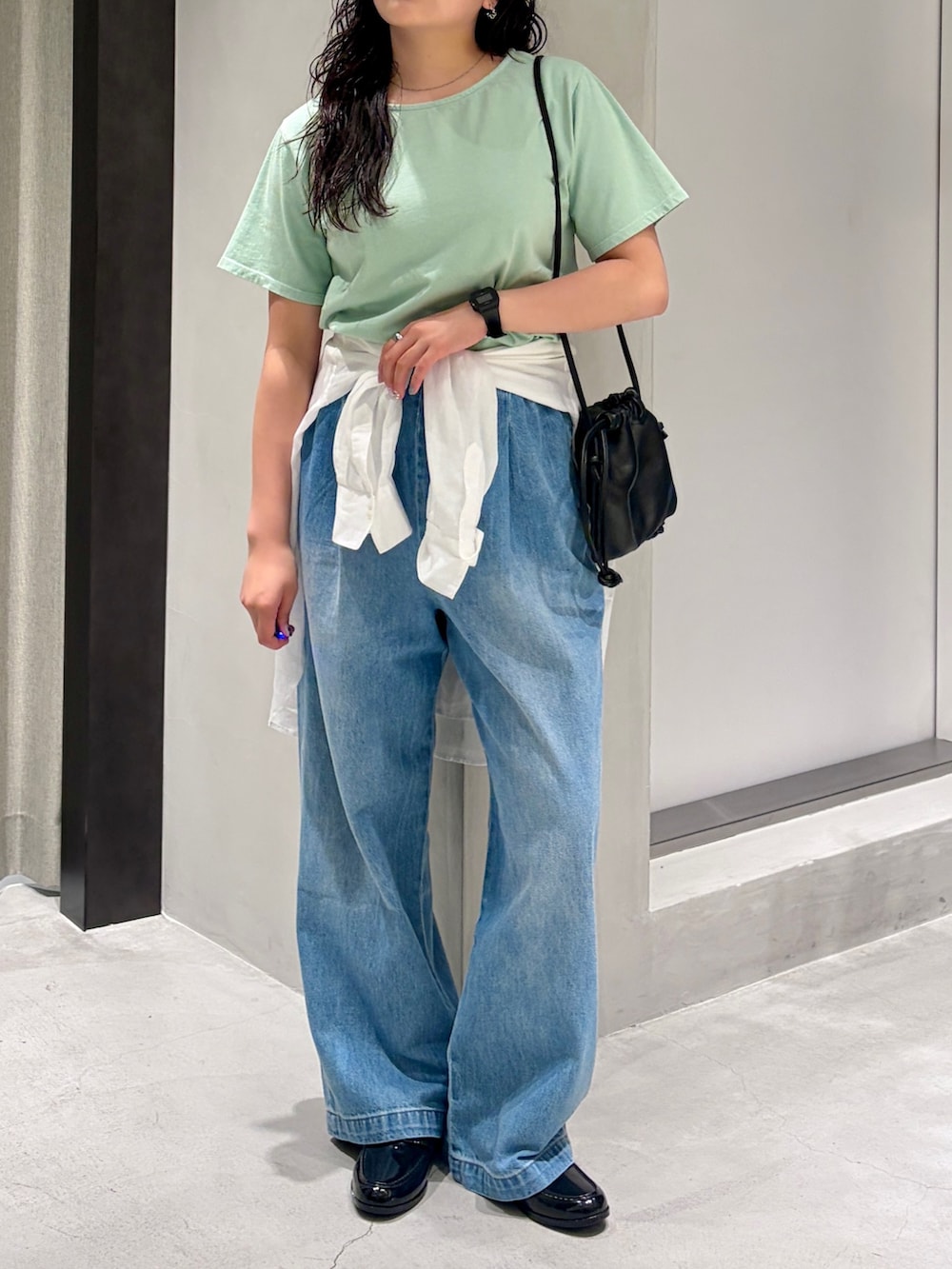 グリーン系のTシャツ/カットソー、ブラック系のショルダーバッグ、ホワイト系のシャツ/ブラウスを着用したレディースの夏コーディネートの6枚目の写真