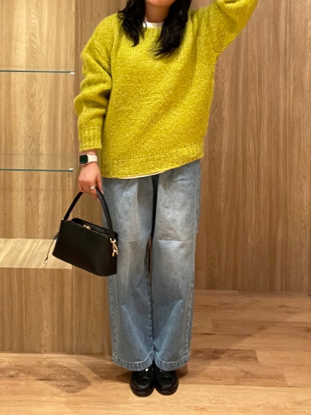イエロー系のニット/セーター、ブラック系のハンドバッグ、ブルー系のデニムパンツを着用したレディースの冬コーディネートの3枚目の写真