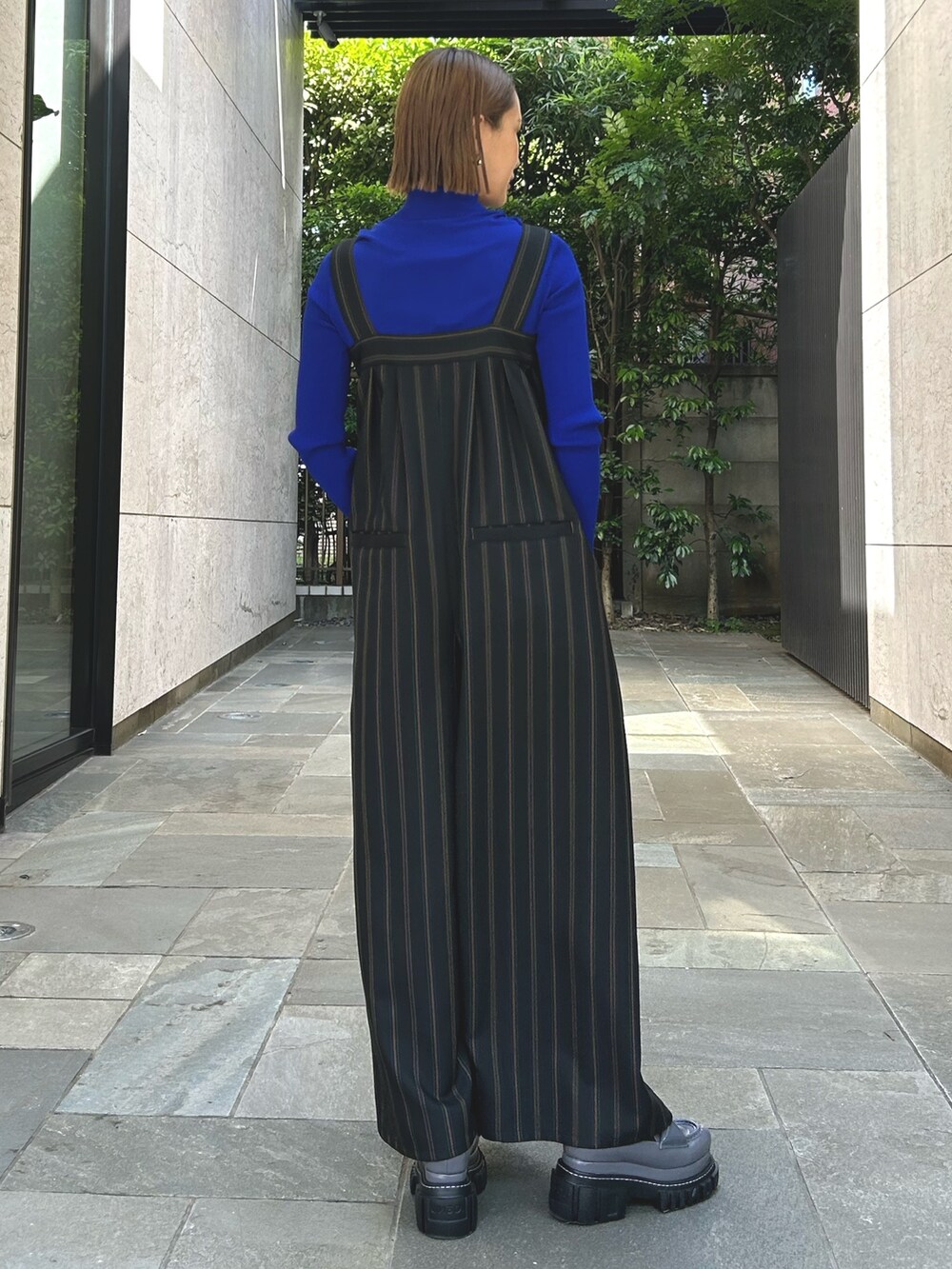 ブラック系のつなぎ/オールインワン、ブルー系のニット/セーターを着用したレディースの春コーディネートの2枚目の写真