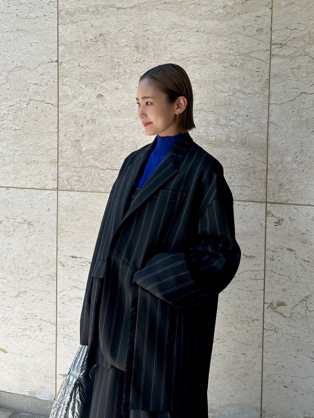 ブラック系のテーラードジャケット、ブラック系のスラックス、シルバー系のハンドバッグを着用したレディースの夏コーディネートの3枚目の写真