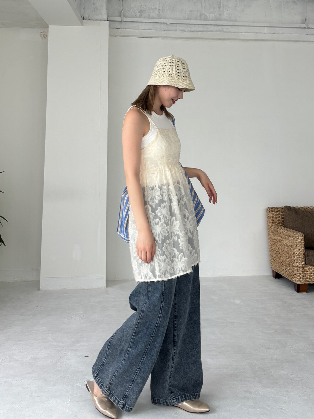 ブルー系のトートバッグ、ホワイト系のチュニック、ブルー系のデニムパンツを着用したレディースの夏コーディネートの3枚目の写真