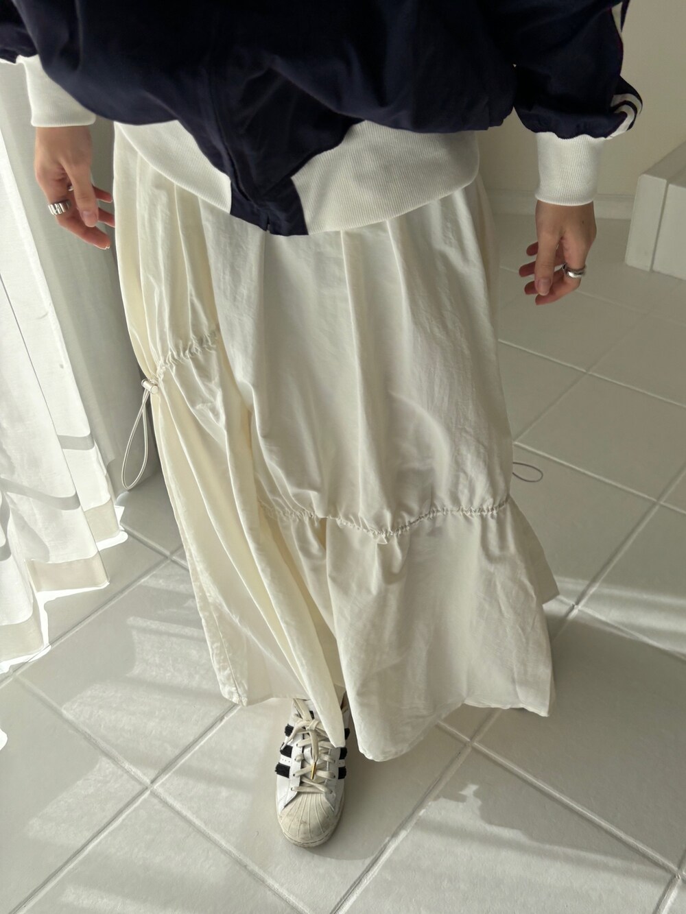 ブルー系のその他アウター、ホワイト系のスカート、ホワイト系のスニーカーを着用したレディースの冬コーディネートの4枚目の写真