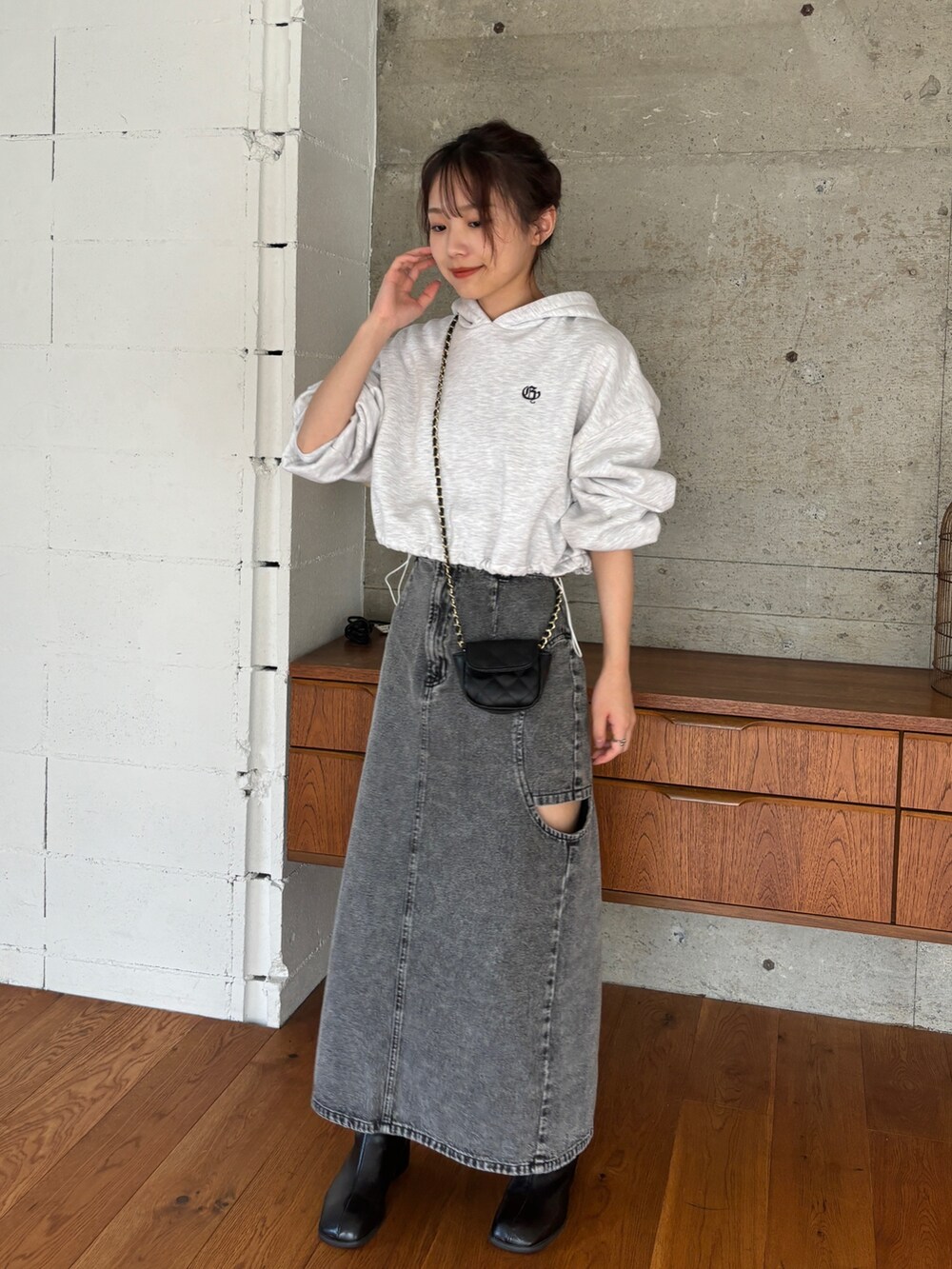 ベージュ系のパーカー、ブラック系のデニムスカート、ブラック系のブーツを着用したレディースの秋コーディネートの3枚目の写真