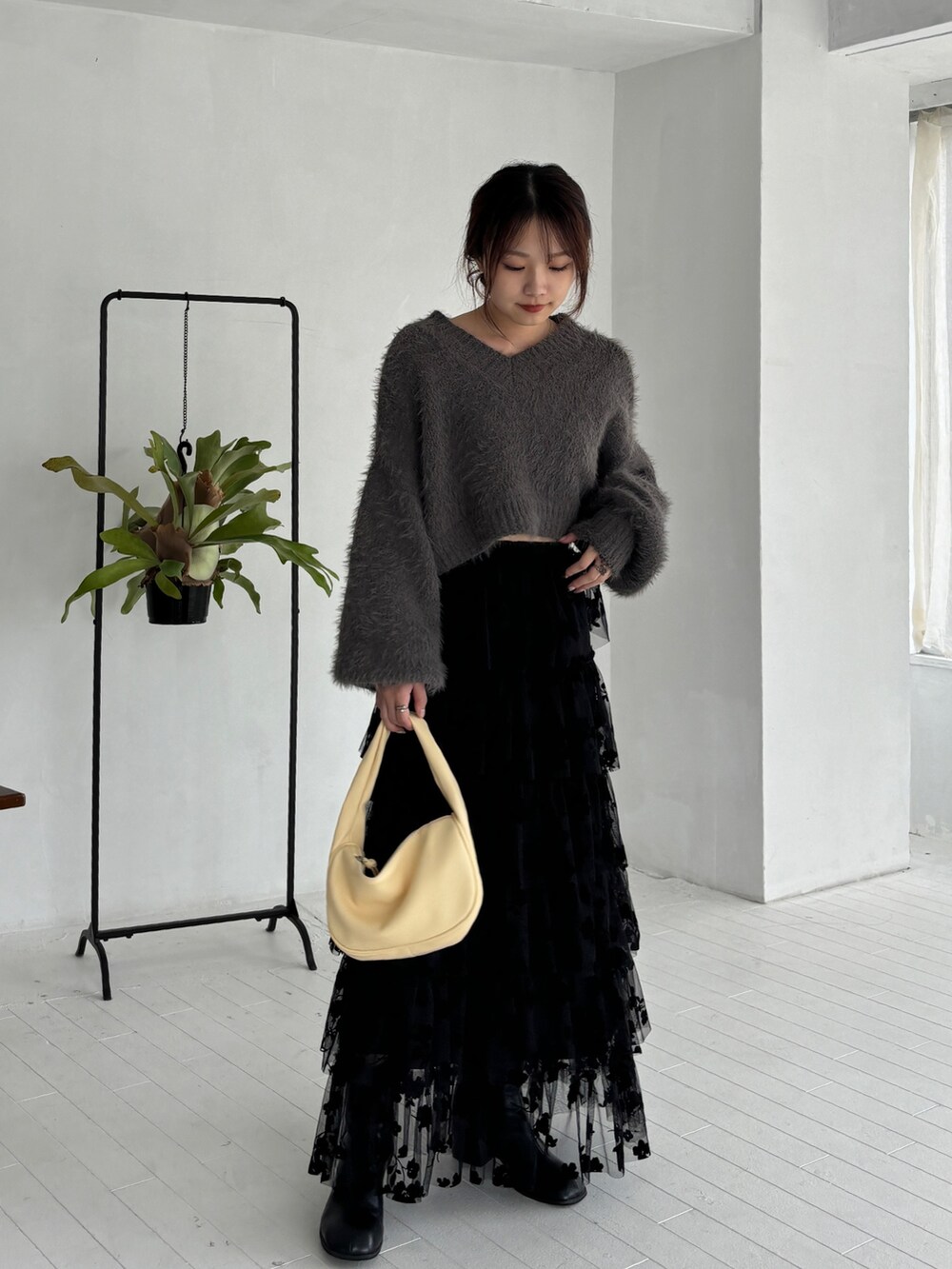 グレー系のニット/セーター、ブラック系のスカート、ブラック系のブーツを着用したレディースの秋コーディネートの2枚目の写真