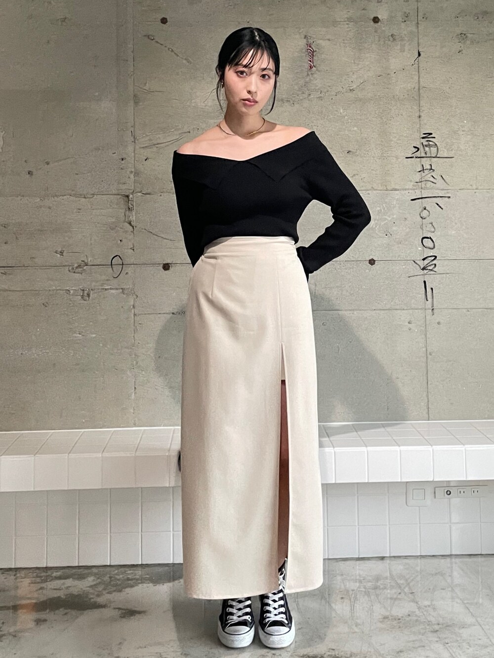 ホワイト系のスカート、ブラック系のスニーカー、ブラック系のニット/セーターを着用したレディースの春コーディネートの2枚目の写真