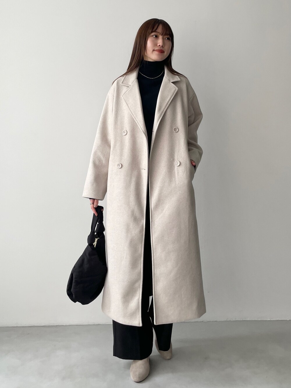 ブルー系のチェスターコート、ホワイト系のニット/セーター、グレー系のスウェットパンツを着用したレディースの冬コーディネートの2枚目の写真