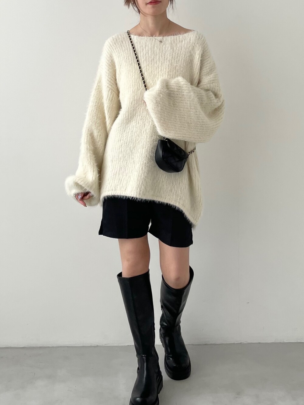 グレー系のデニムパンツ、グリーン系のニット/セーター、ブラック系のスニーカーを着用したレディースの冬コーディネートの3枚目の写真