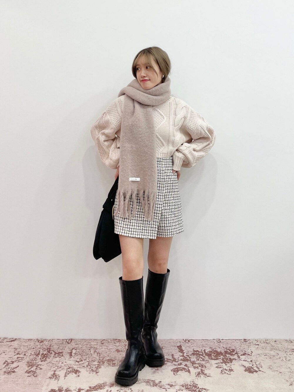 ホワイト系のニット/セーター、ブラック系のブーツ、ブラック系のハンドバッグを着用したレディースの秋コーディネートの2枚目の写真