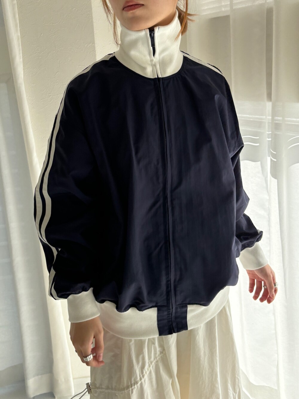 ブルー系のその他アウター、ホワイト系のスカート、ホワイト系のスニーカーを着用したレディースの冬コーディネートの3枚目の写真