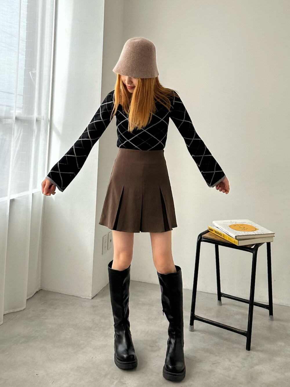 ブラウン系のスカート、ブラック系のニット/セーター、ブラック系のブーツを着用したレディースの冬コーディネートの2枚目の写真