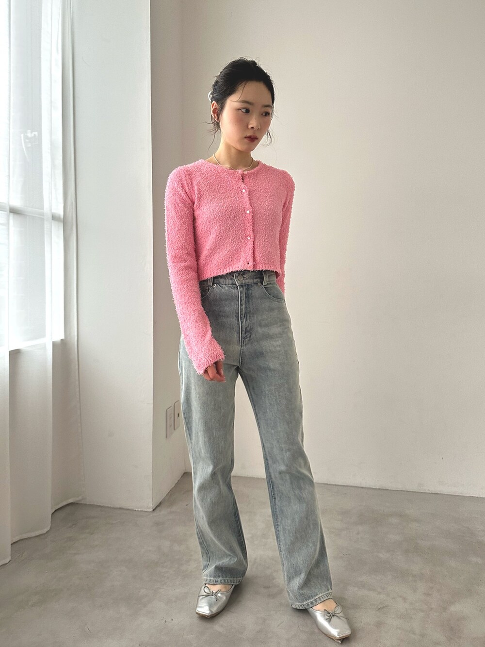 ブルー系のデニムパンツ、シルバー系のバレエシューズ、ピンク系のカーディガン/ボレロを着用したレディースの秋コーディネートの2枚目の写真