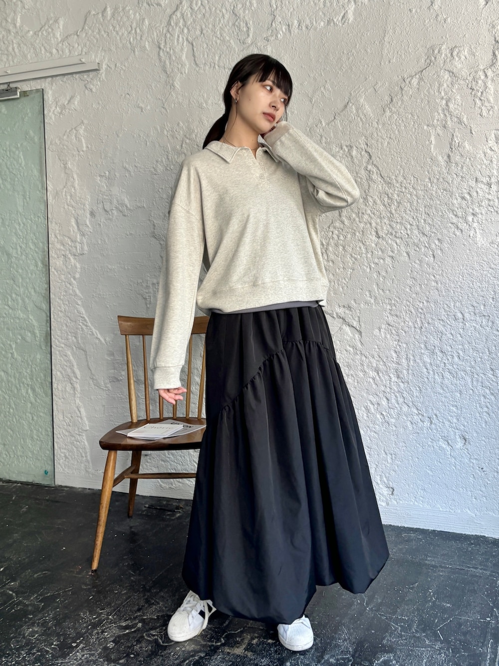 ブラック系のスカート、ホワイト系のスニーカー、ベージュ系のポロシャツを着用したレディースの冬コーディネートの4枚目の写真