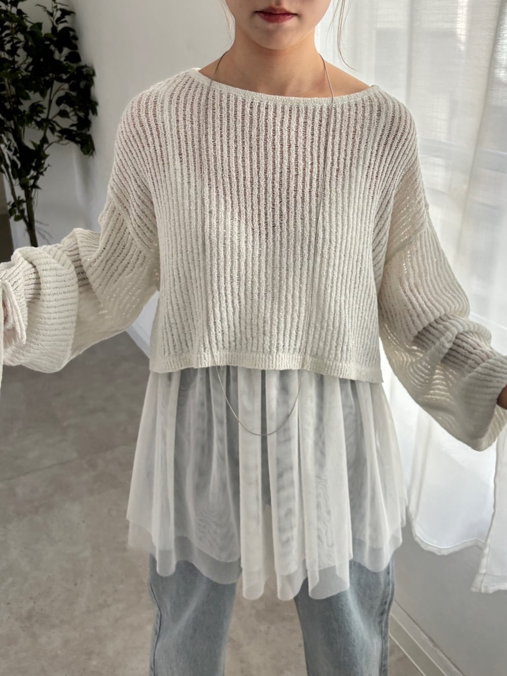 ホワイト系のシャツ/ブラウス、ホワイト系のニット/セーター、ブルー系のデニムパンツを着用したレディースの春コーディネートの4枚目の写真