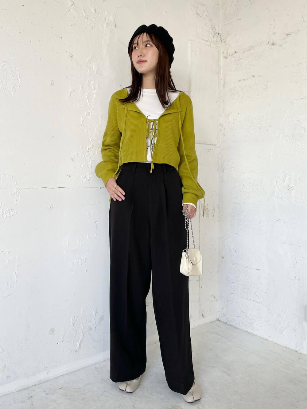 ベージュ系のニット/セーター、ブラック系のスニーカー、ホワイト系のTシャツ/カットソーを着用したレディースの秋コーディネートの2枚目の写真