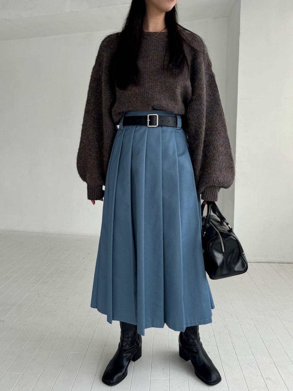 ブラウン系のニット/セーター、ブルー系のスカート、ブラック系のブーツを着用したレディースの秋コーディネートの3枚目の写真