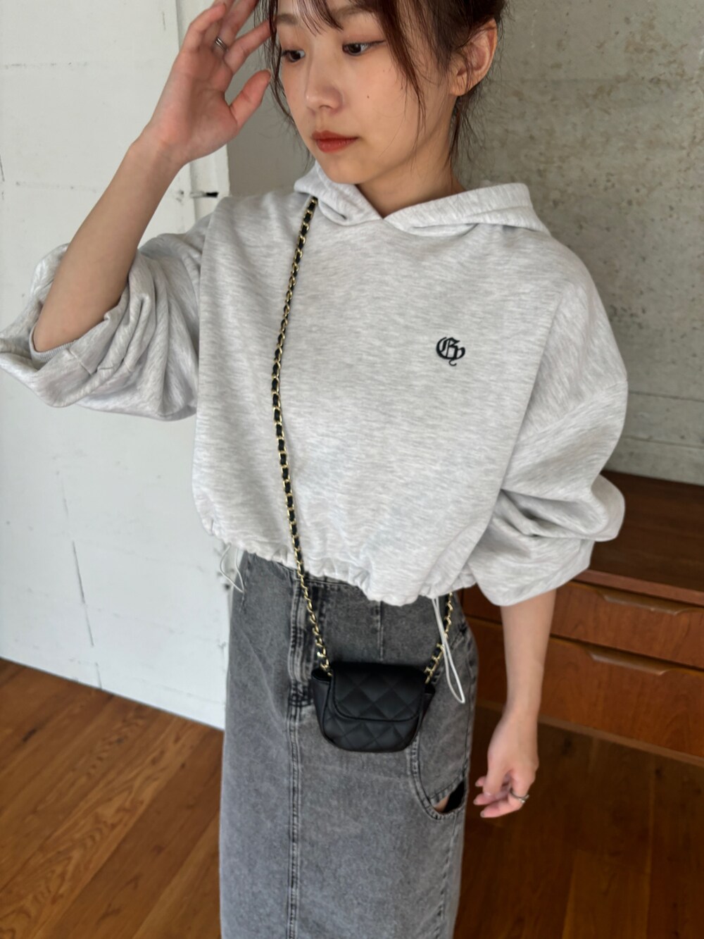 ベージュ系のパーカー、ブラック系のデニムスカート、ブラック系のブーツを着用したレディースの秋コーディネートの4枚目の写真