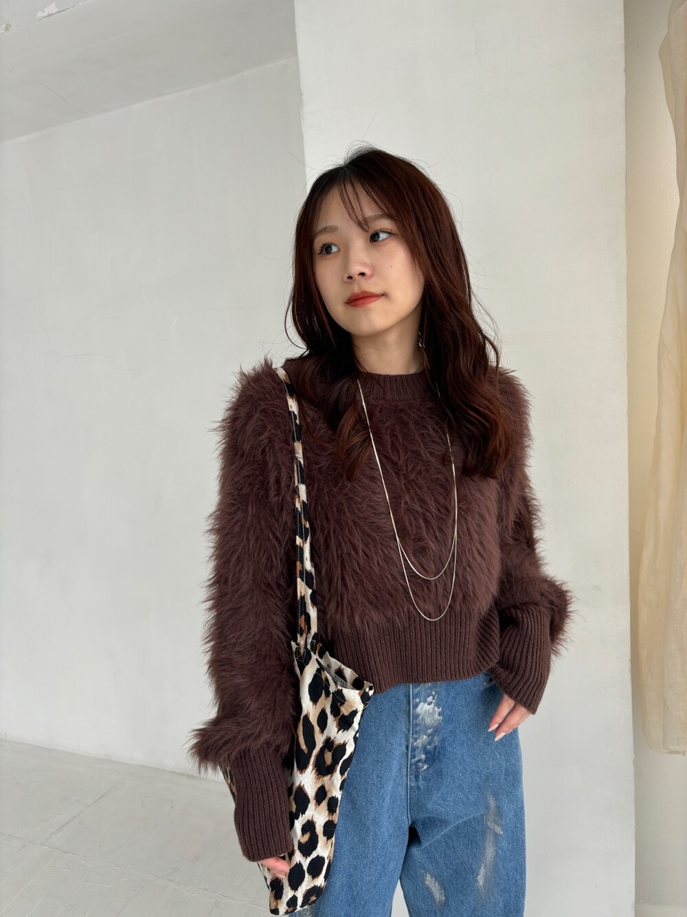 ブラウン系のニット/セーター、ブルー系のデニムパンツ、ホワイト系のスニーカーを着用したレディースの秋コーディネートの4枚目の写真