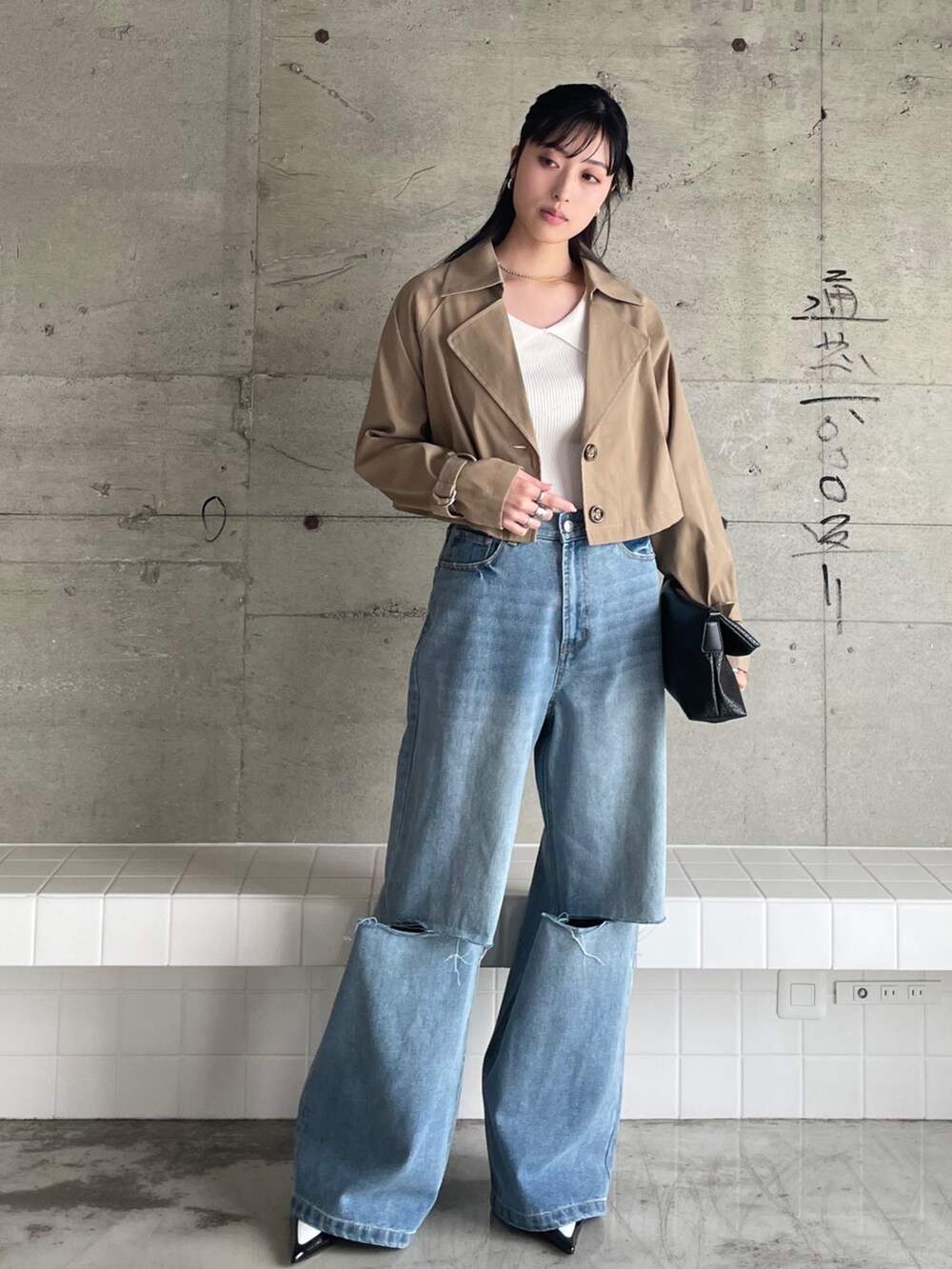 ベージュ系のトレンチコート、ホワイト系のニット/セーター、ブルー系のデニムパンツを着用したレディースの春コーディネートの3枚目の写真